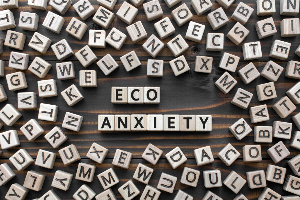 Eco-anxiety written out with wooden blocks with letters, anxiety about ecological disasters natural environment pollution and climate change, eco anxiety concept, random letters around, top view wooden background